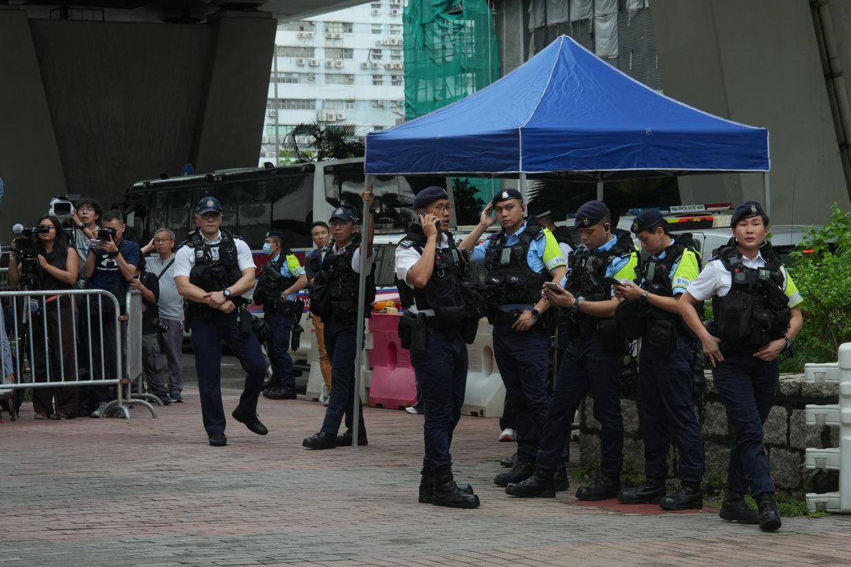 Hong Kong police arrest woman for seditious T-shirt outside court as democracy activists face conviction